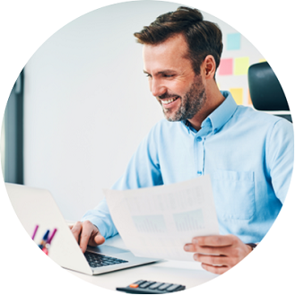 Un homme tient une feuille de papier tout en regardant un portable. 