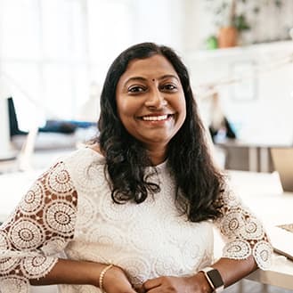 Commited to your success. A smiling customer service representative facing the camera while seated at a desk.