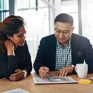 Compliance is critical Two people seated at a table looking at a chart.